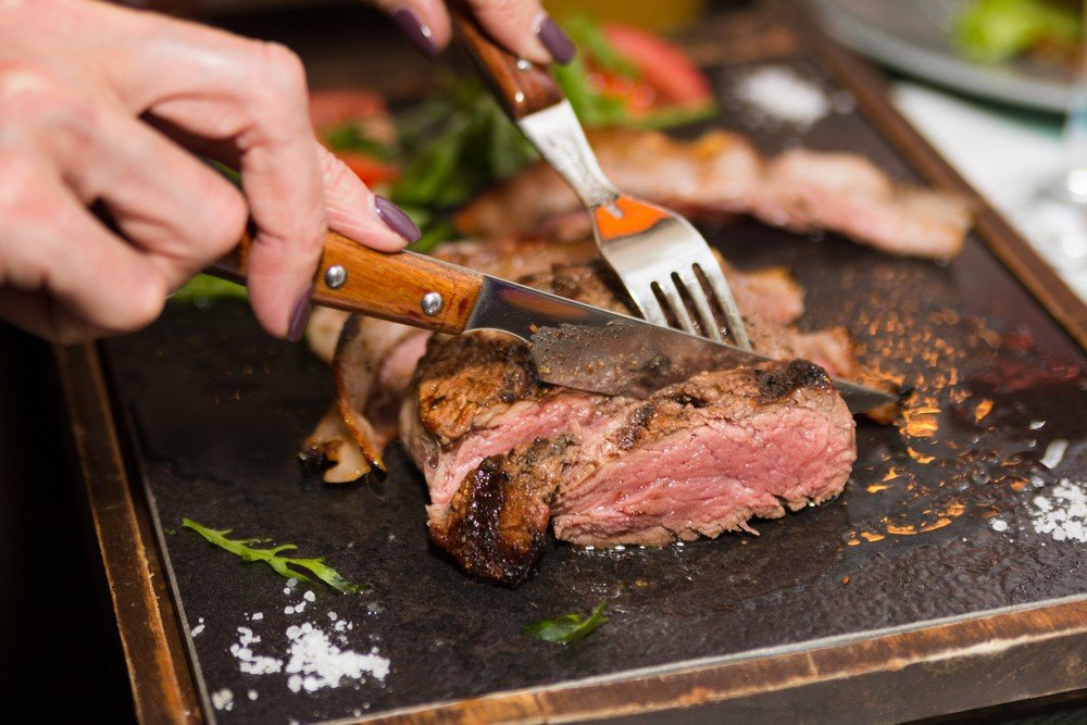 Есть мясо с ножа. Мясо стейк. Жареное мясо.